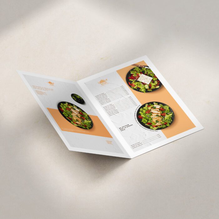 Une brochure pliée avec une image d'une salade sur la couverture. Le texte "KOR LA SOHNS VOIC" est également visible sur la couverture